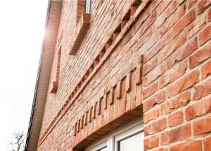 Detailaufnahme einer roten Klinkerfassade mit Ziermauerwerk